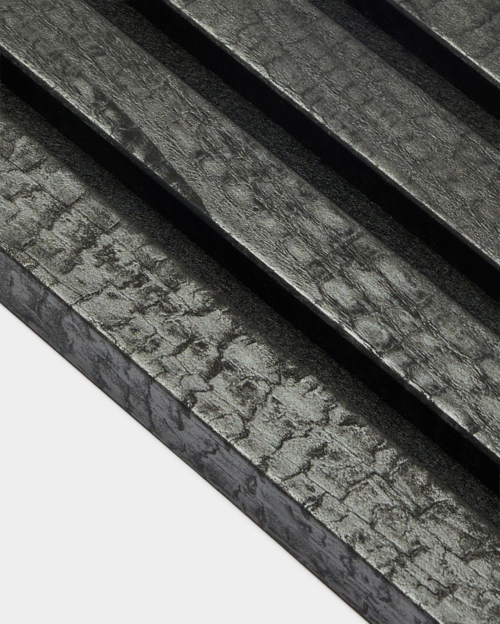 WoodUpp Akupanel eindlamel in Charcoal (2,2 cm), met diagonale, getextureerde akoestische houten panelen met een geblakerde black afwerking voor wandmontage.